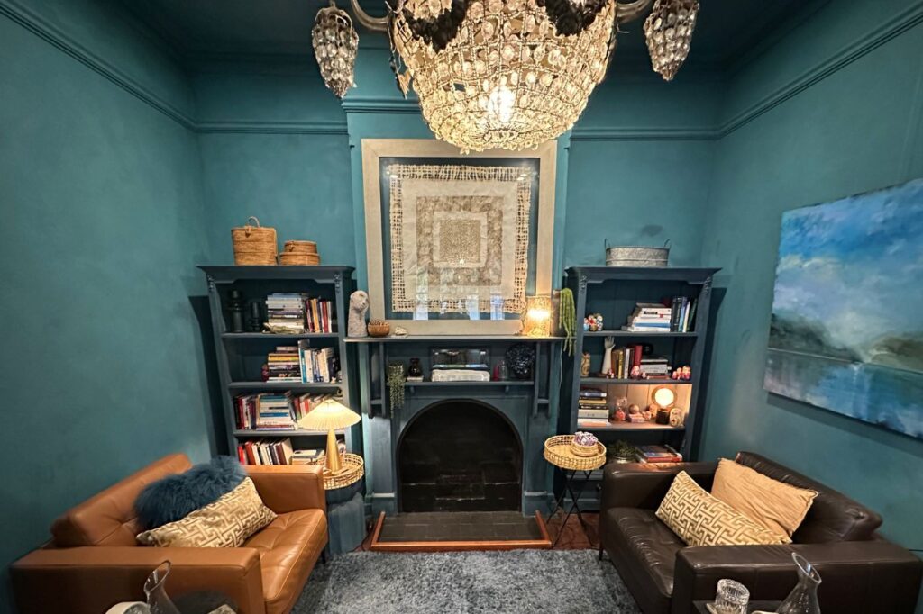 Therapy room painted in Aubusson blue with two leather chairs facing each other in front of a cozy fireplace